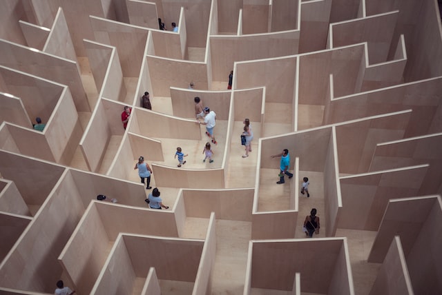 Children and adults navigating a complex wooden maze, illustrating challenges in enterprise resource planning (ERP) implementation and the need for effective strategies.
