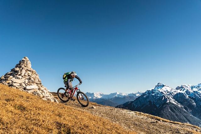 Mountain biker navigating a rocky trail with snow-capped mountains in the background, emphasizing adventure and outdoor activity related to ERP implementation preparation.