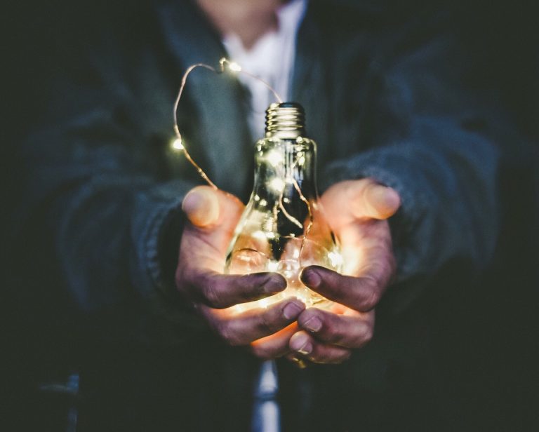 Person holding a glowing light bulb with fairy lights, symbolizing innovative ideas and the transformative potential of ERP systems.