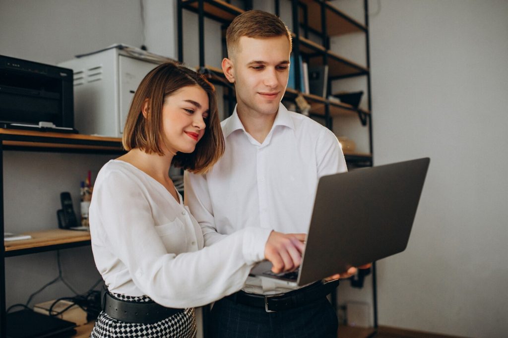Female and male colleagues collaborating on a laptop in a modern office setting, reflecting teamwork and digital transformation relevant to ERP solutions.